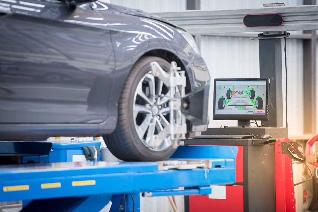 Car Mechanic Installing Sensor During Suspension Adjustment.